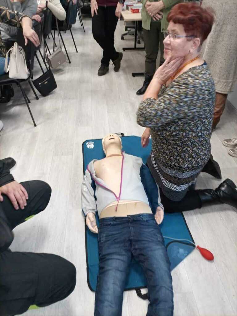 Kobieta klęczy przed manekinem do ćwiczeń resuscytacji krążeniowo-oddechowej